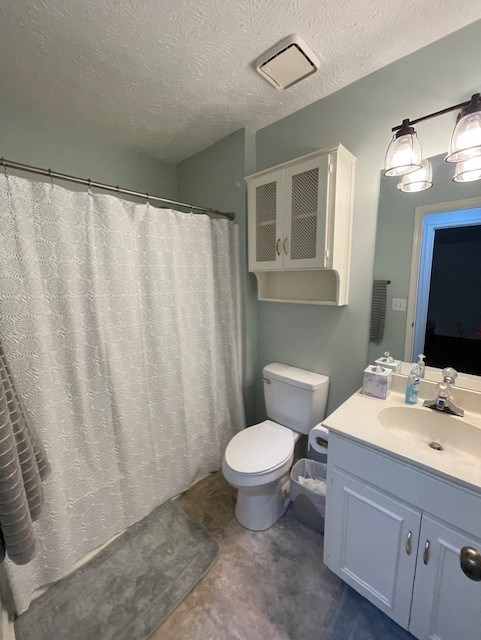 full bathroom with toilet, a textured ceiling, vanity, and curtained shower