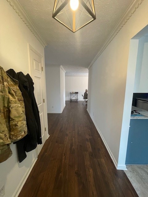 corridor with crown molding, wood finished floors, baseboards, and a textured ceiling