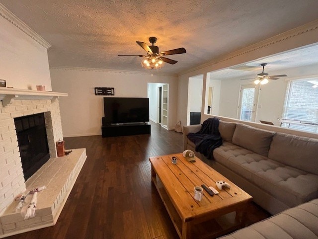 living room with dark wood-type flooring, a brick fireplace, ornamental molding, and a textured ceiling