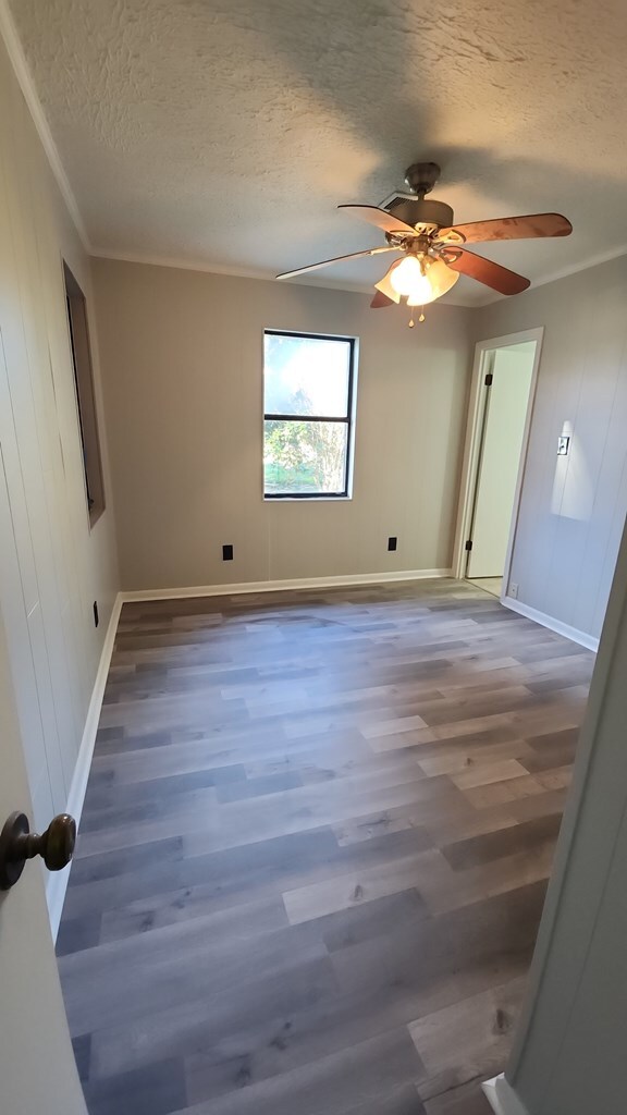 166 Pine Ridge Dr, Union Springs, AL 36089 - unfurnished room featuring a textured ceiling, wood finished floors, a ceiling fan, crown molding, and baseboards