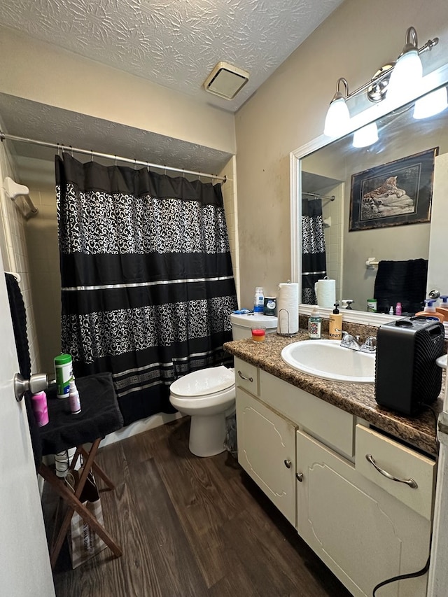 full bathroom with a textured ceiling, toilet, wood finished floors, vanity, and a shower with curtain