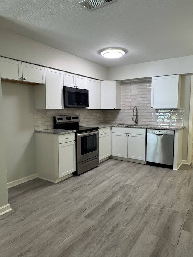 1508 Emerson Ave, Columbus, GA 31907 - kitchen with stainless steel appliances, tasteful backsplash, white cabinetry, and a textured ceiling