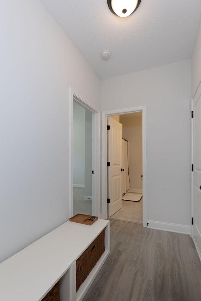 hall featuring light wood-style flooring and baseboards