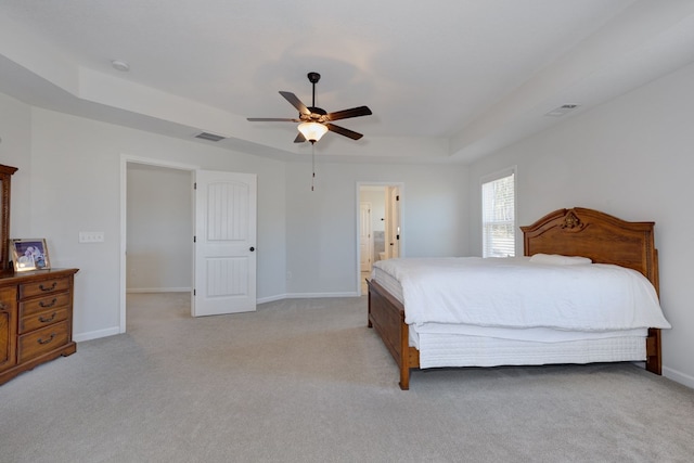 bedroom with light carpet, visible vents, baseboards, and a tray ceiling