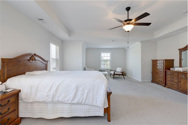 bedroom with visible vents, light carpet, a raised ceiling, and baseboards