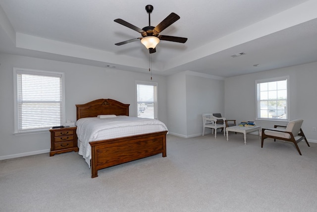 bedroom featuring a tray ceiling, baseboards, visible vents, and light carpet