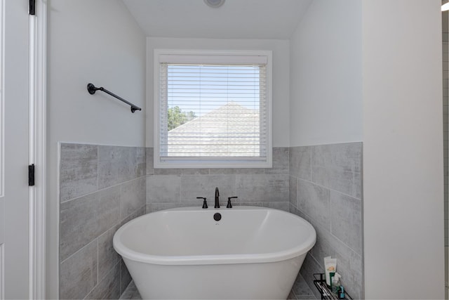 full bathroom featuring a wainscoted wall, a freestanding bath, and tile walls