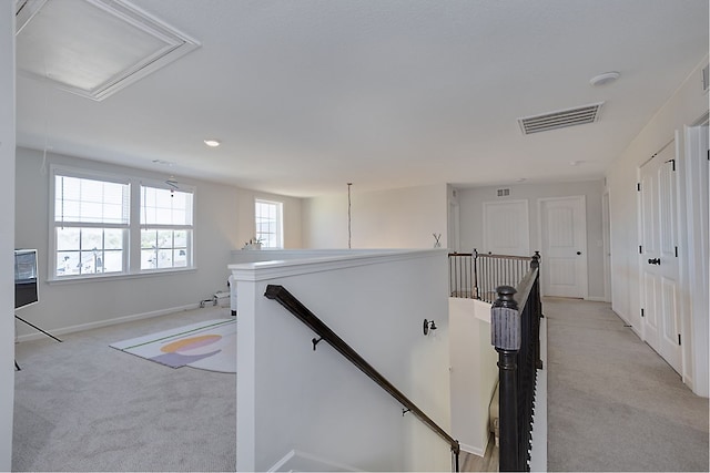 corridor with visible vents, baseboards, attic access, an upstairs landing, and light colored carpet