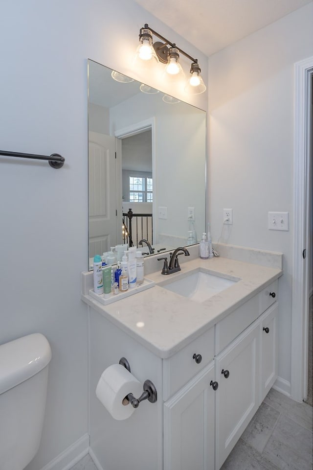 bathroom featuring baseboards, toilet, marble finish floor, and vanity