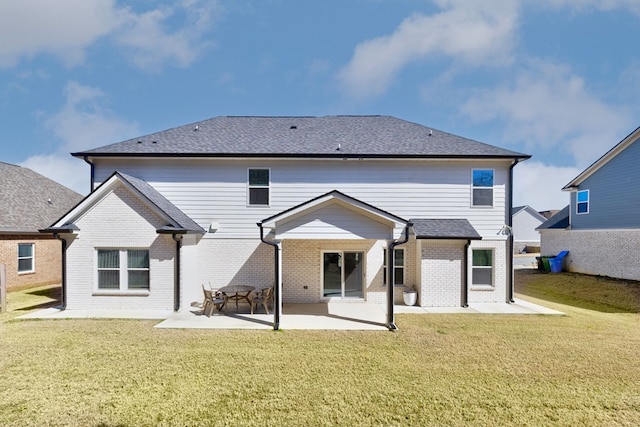 back of property featuring a yard, brick siding, a shingled roof, and a patio area