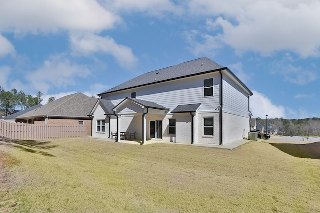 rear view of house with cooling unit, fence, a yard, a patio area, and brick siding