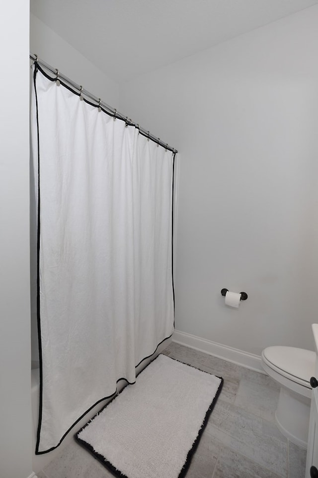 bathroom featuring curtained shower, baseboards, toilet, and wood finished floors