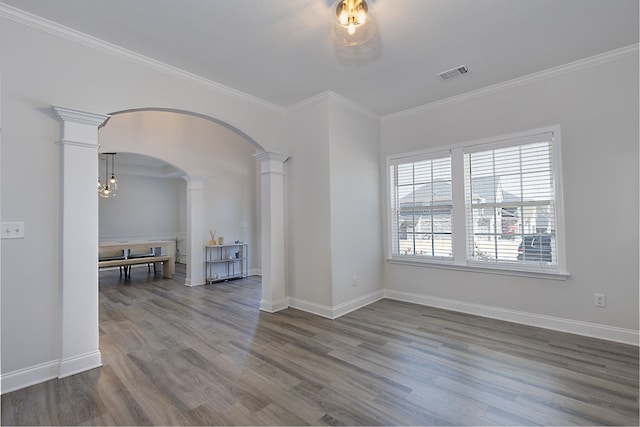 spare room featuring arched walkways, visible vents, ornate columns, and wood finished floors