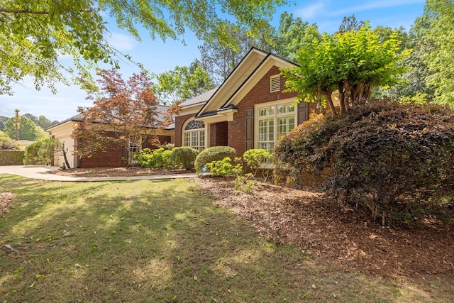 view of front of property featuring a garage, a front yard, brick siding, and driveway