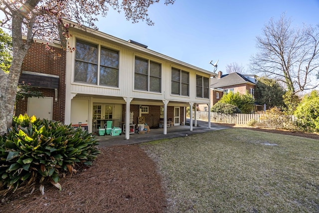 rear view of house featuring a patio area, brick siding, and fence