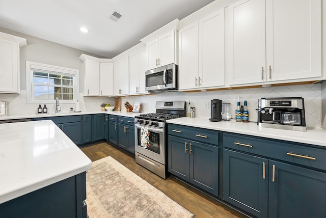 2013 Hereford Ln, Columbus, GA 31904 - kitchen with appliances with stainless steel finishes, blue cabinets, white cabinets, tasteful backsplash, and light countertops