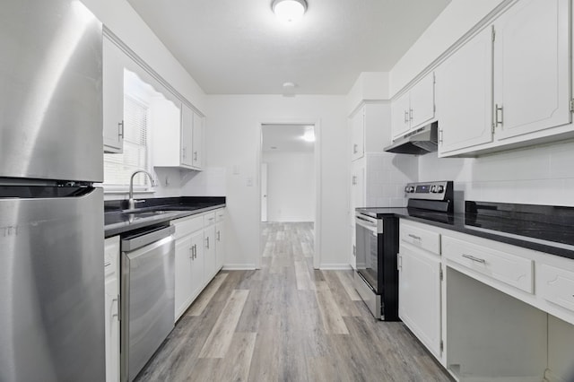 5202 Lakeshore Rd, Columbus, GA 31907 - kitchen with appliances with stainless steel finishes, under cabinet range hood, dark countertops, a sink, and light wood-style floors