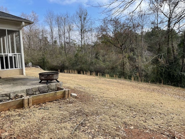 view of yard featuring a fire pit and a sunroom