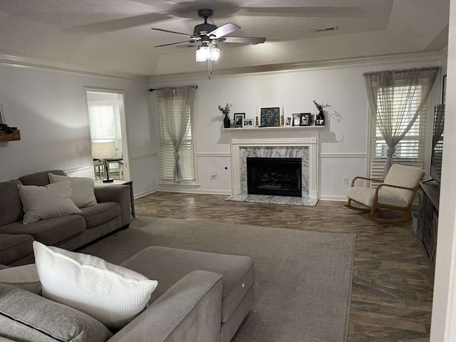 living room with ornamental molding, a wealth of natural light, ceiling fan, and a fireplace