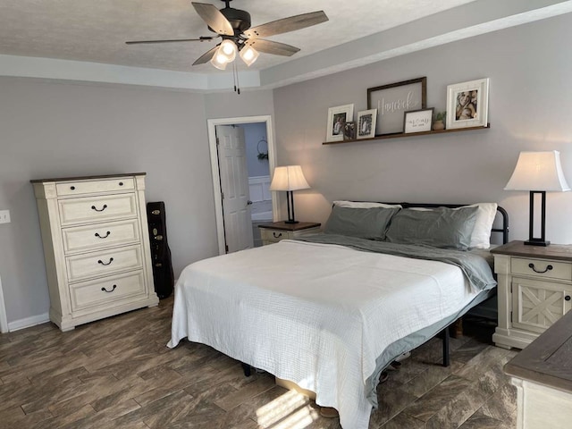 bedroom featuring ceiling fan, a tray ceiling, dark hardwood / wood-style flooring, and a textured ceiling