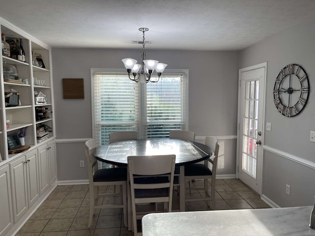 tiled dining room featuring a textured ceiling and a chandelier