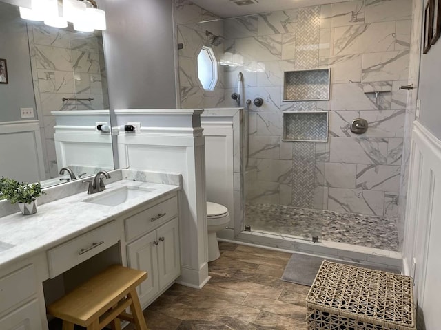 bathroom with vanity, toilet, and tiled shower