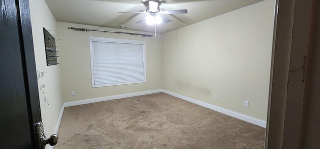 carpeted spare room with visible vents, baseboards, and a ceiling fan