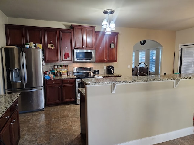 kitchen with stainless steel appliances, dark brown cabinets, decorative backsplash, and a kitchen breakfast bar