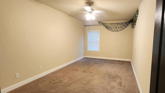 carpeted spare room featuring baseboards and a ceiling fan