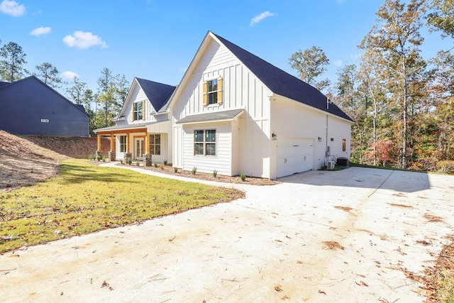 rear view of house featuring covered porch, a garage, a lawn, and central air condition unit