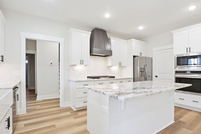 kitchen with appliances with stainless steel finishes, a center island, light hardwood / wood-style floors, and white cabinetry