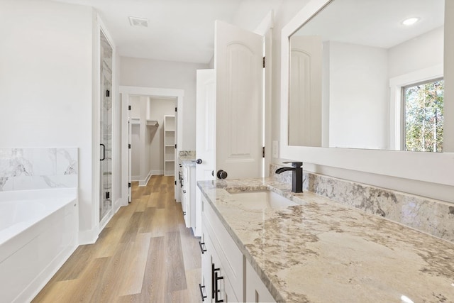 bathroom with a bath, vanity, and wood-type flooring