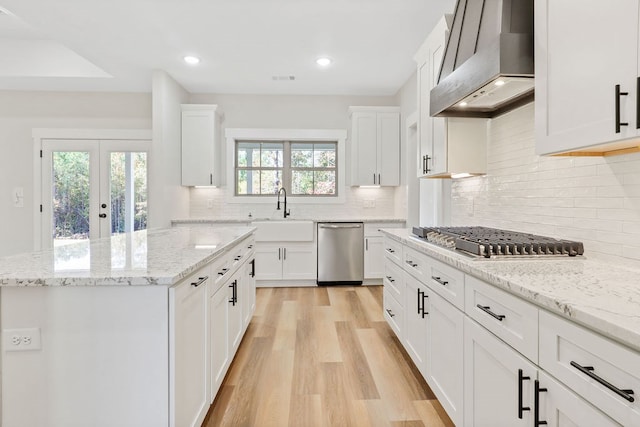 kitchen featuring white cabinets, sink, wall chimney range hood, and stainless steel appliances