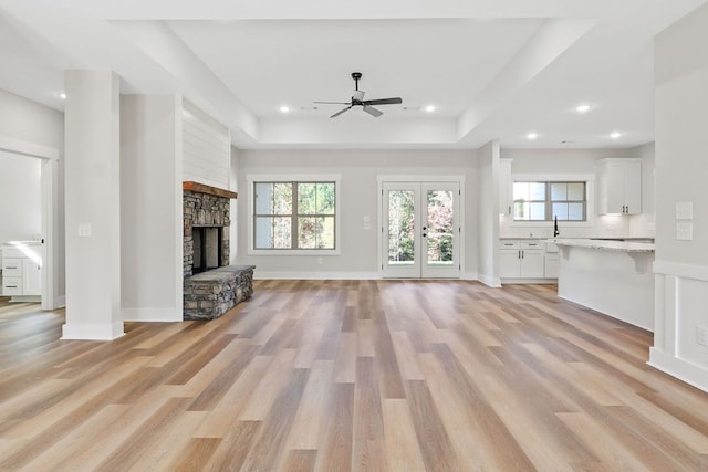 unfurnished living room with a fireplace, light hardwood / wood-style floors, ceiling fan, and a healthy amount of sunlight