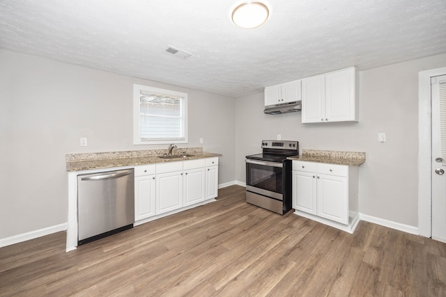 7 Magnolia St, Columbus, GA 31904 - kitchen with stainless steel appliances, light wood-style flooring, a textured ceiling, white cabinets, and light stone counters