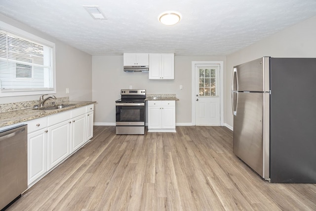 7 Magnolia St, Columbus, GA 31904 - kitchen featuring appliances with stainless steel finishes, light wood-type flooring, white cabinets, light stone counters, and a textured ceiling