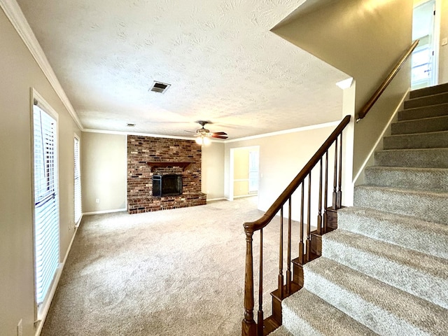 stairs featuring visible vents, ornamental molding, carpet, a textured ceiling, and a brick fireplace