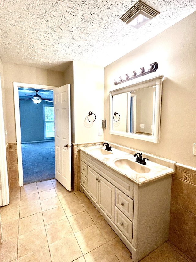 7396 Cedar Creek Loop, Columbus, GA 31904 - bathroom with wainscoting, a textured ceiling, tile patterned flooring, double vanity, and a ceiling fan