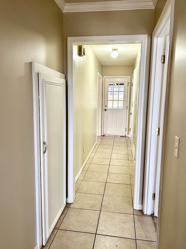 hallway with light tile patterned floors, baseboards, and crown molding