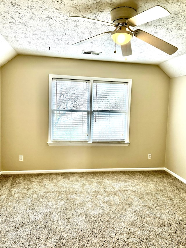 unfurnished room featuring visible vents, ceiling fan, carpet, vaulted ceiling, and a textured ceiling