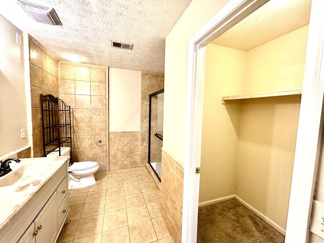 bathroom featuring tile walls, visible vents, a stall shower, a textured ceiling, and vanity