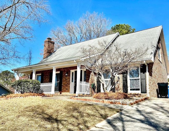 view of front of property with a chimney, a front lawn, and brick siding