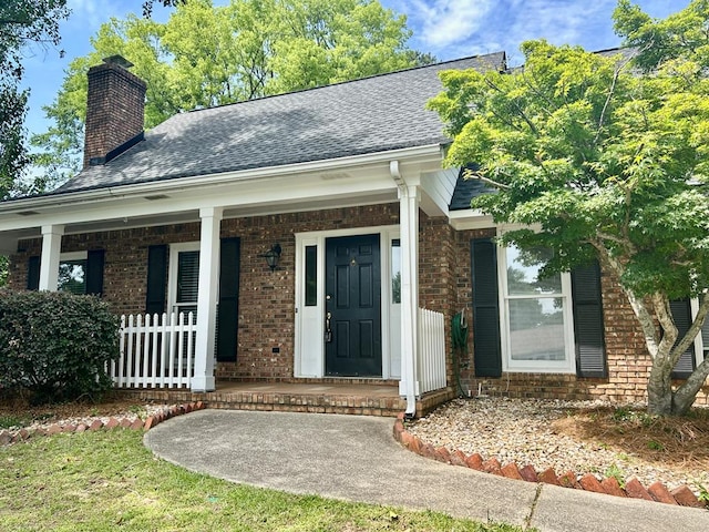 7396 Cedar Creek Loop, Columbus, GA 31904 - view of exterior entry with brick siding, a shingled roof, a chimney, and covered porch