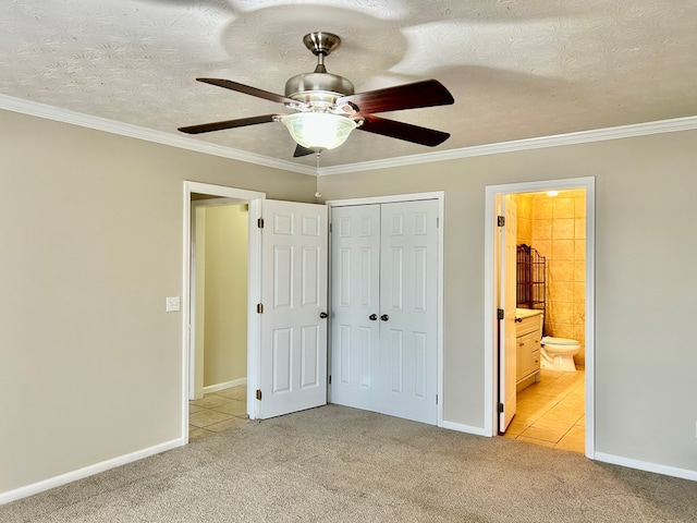 unfurnished bedroom featuring a textured ceiling, light colored carpet, baseboards, ornamental molding, and a closet