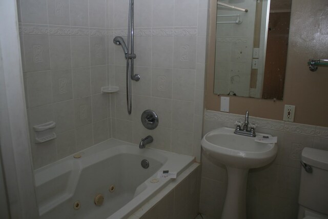 bathroom featuring tiled shower / bath, tile walls, and toilet