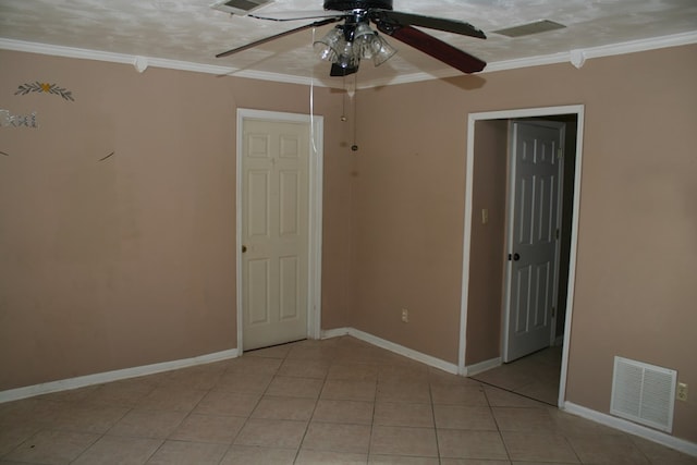 empty room featuring ceiling fan, ornamental molding, a textured ceiling, and light tile patterned floors