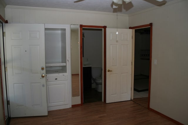 unfurnished bedroom with connected bathroom, dark hardwood / wood-style floors, ceiling fan, and ornamental molding