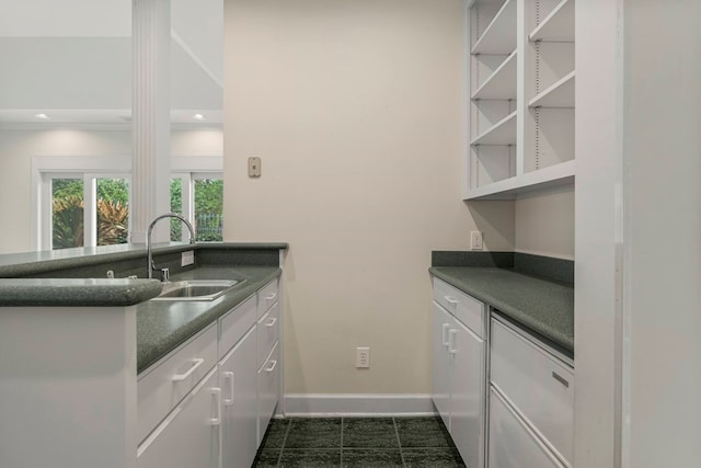 kitchen featuring dark countertops, a sink, baseboards, white cabinets, and open shelves