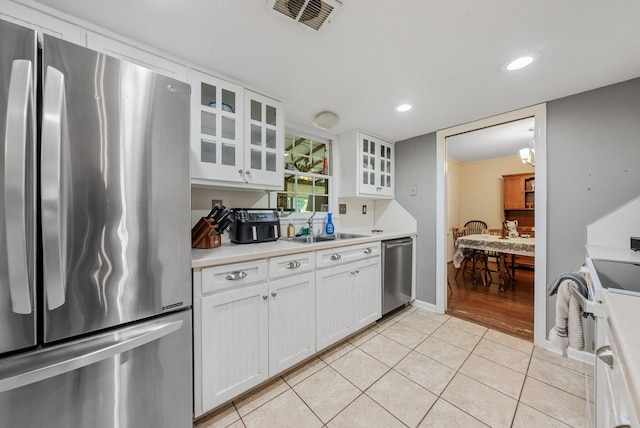 438 Newport Pl, Columbus, GA 31904 - kitchen featuring stainless steel appliances, a sink, light tile patterned floors, white cabinetry, and light countertops
