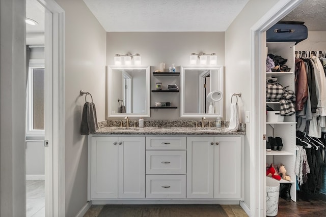 6538 Middleburg Dr, Columbus, GA 31909 - bathroom with double vanity, a spacious closet, baseboards, and a textured ceiling